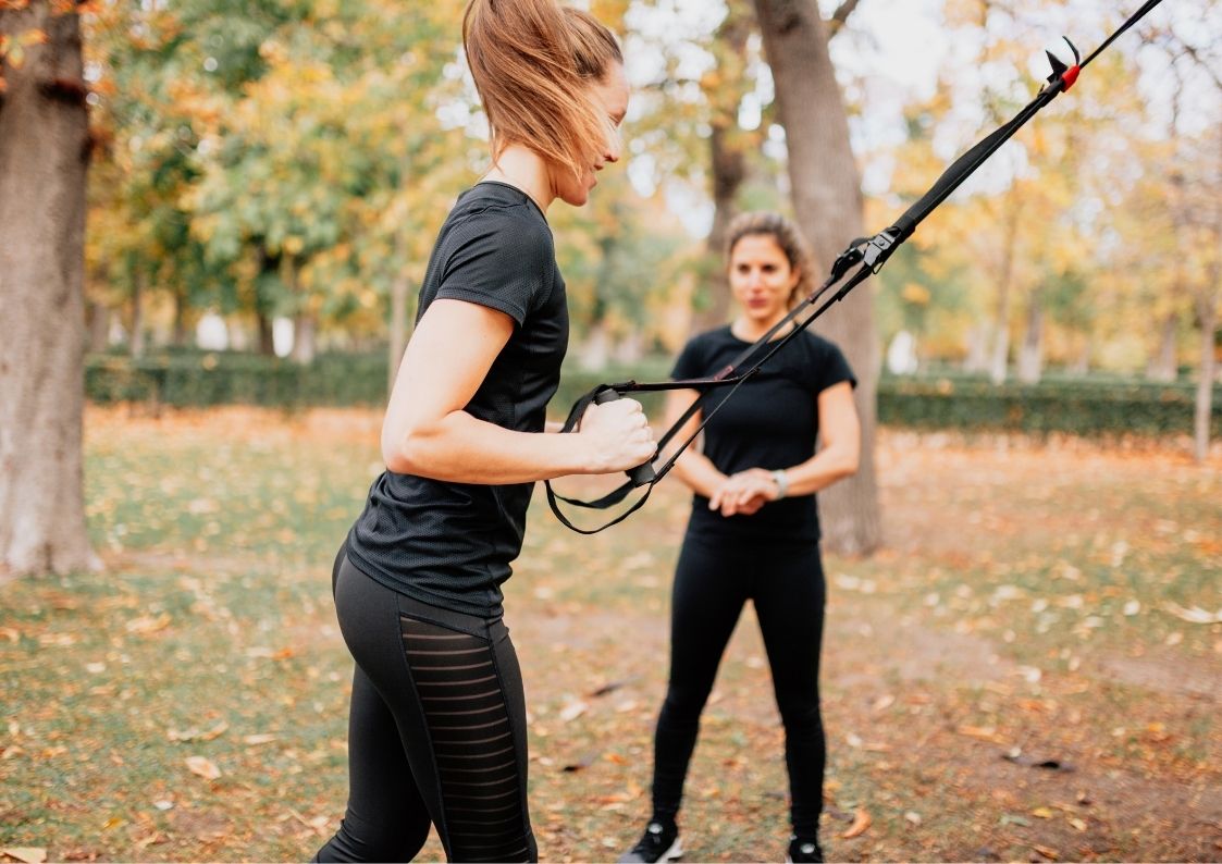 Vrouwelijke personal trainer geeft een personal training in het bos